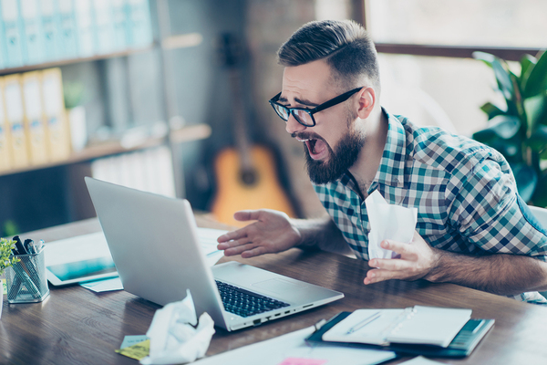 Man appearing surprised while looking at his laptop computer.